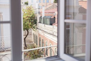 A window view of a building with a tree, balconies, and a red-tiled roof. - FLH Príncipe Real with View (Lisbon)
