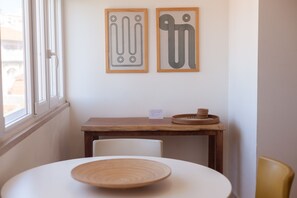 A room with a round table, two chairs, a wooden side table, and two framed abstract artworks on the wall. - FLH Príncipe Real with View (Lisbon)