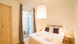 Ein Schlafzimmer mit einem großen Bett, einer Pendelleuchte, zwei Nachttischen und Holzboden.
