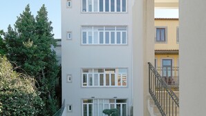 A multi-story building with a courtyard, featuring a staircase with a wrought iron railing, benches, and a small tree. - FLH Porto Balcony Apartment (Oporto)