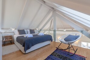 Relax in this spacious loft-style bedroom with a large bed, bedside table, and comfortable chair.