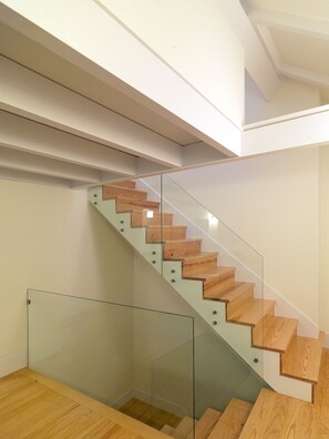 A modern staircase with wooden steps and glass railings.