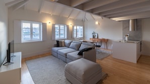 A modern living room with a sectional sofa, a dining area, and a kitchen island. - FLH Douro View Luxury Duplex (Oporto)