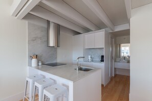 Enjoy cooking in the kitchen with a sleek island and compact range hood, and unwind in the adjacent bathroom with a large mirror and white sink.