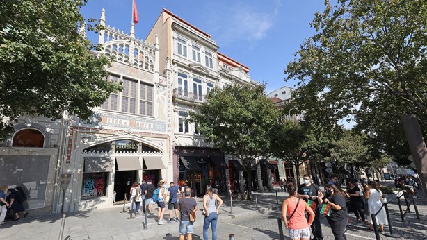Una plaza pública con un edificio histórico que presenta arquitectura ornamentada y una gran entrada.