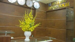 A reception area with a wooden wall, a reception desk, and a sign that reads "HOTEL NOCOM NAM". - Ngoc Nam Hotel (La Gi)