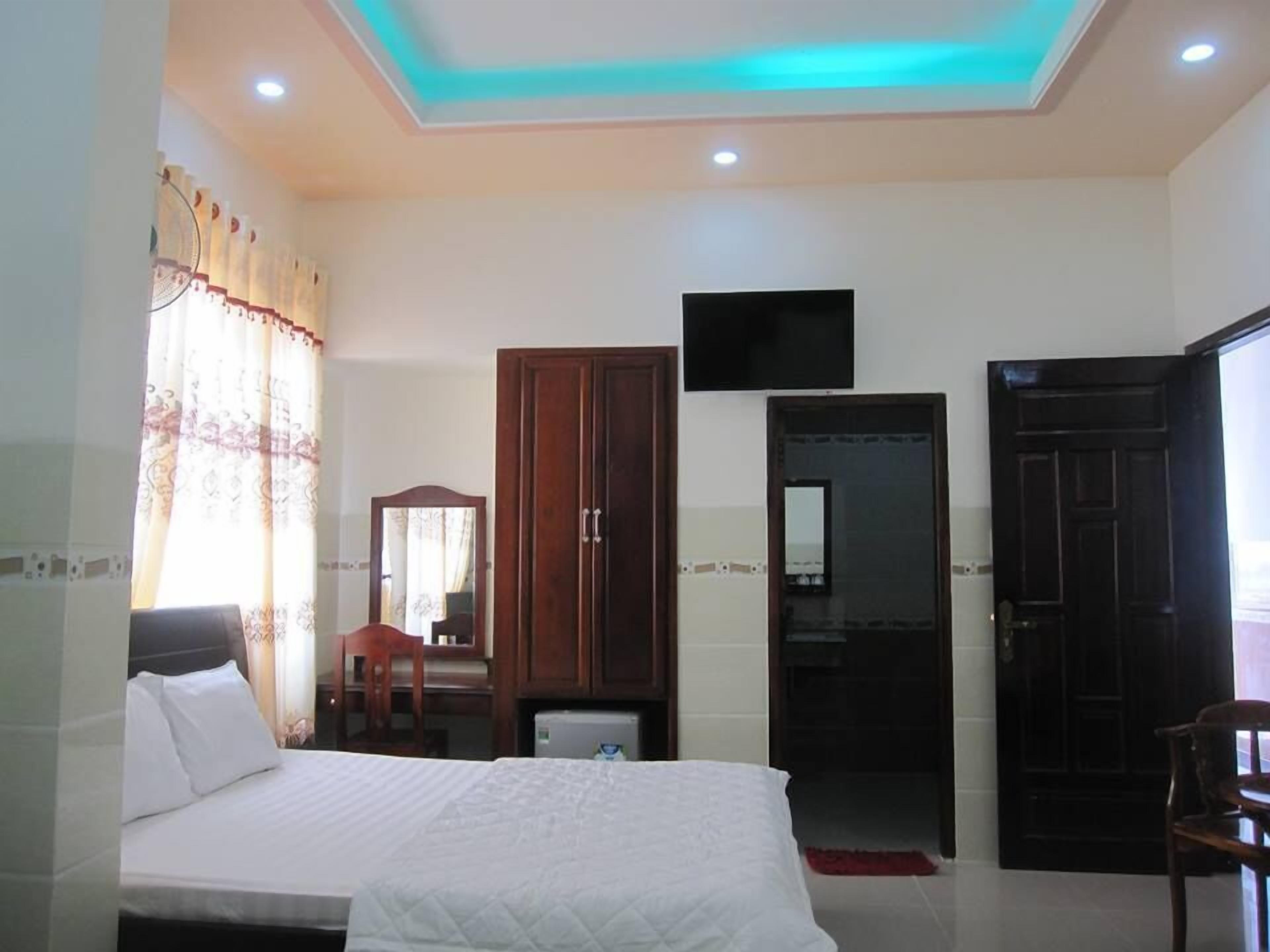 Una habitación de hotel con una cama, un armario, un televisor y una puerta.