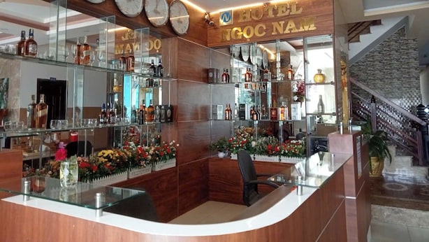 A hotel lobby with a reception desk, multiple clocks, and a staircase. - Ngoc Nam Hotel (La Gi)