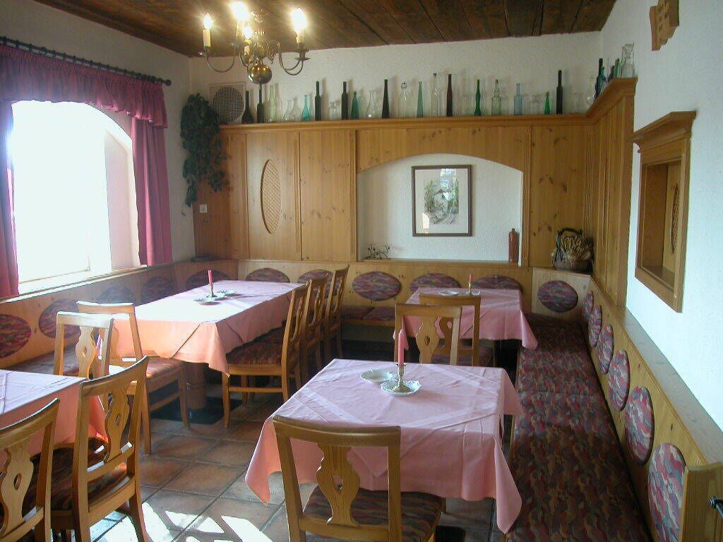 Un comedor con mesas y sillas de madera, un banco y una pared decorada con botellas.