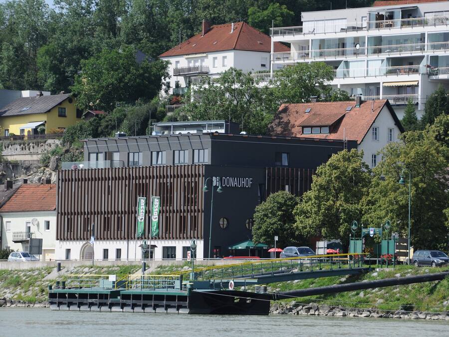 A modern building with a prominent 'DONAUHOF' sign, surrounded by residential buildings and greenery.