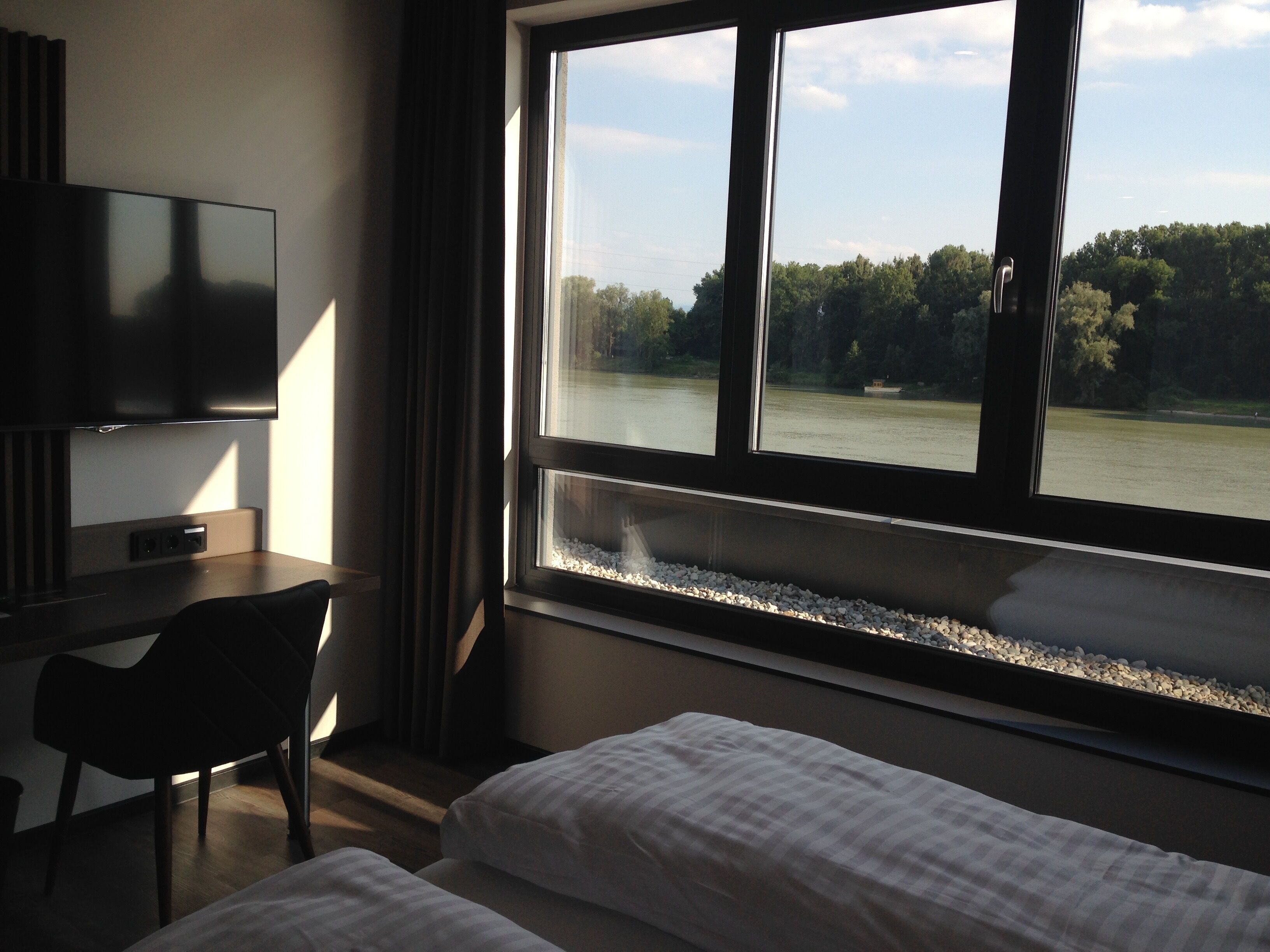 A hotel room with a bed, a desk, a chair, and a TV.