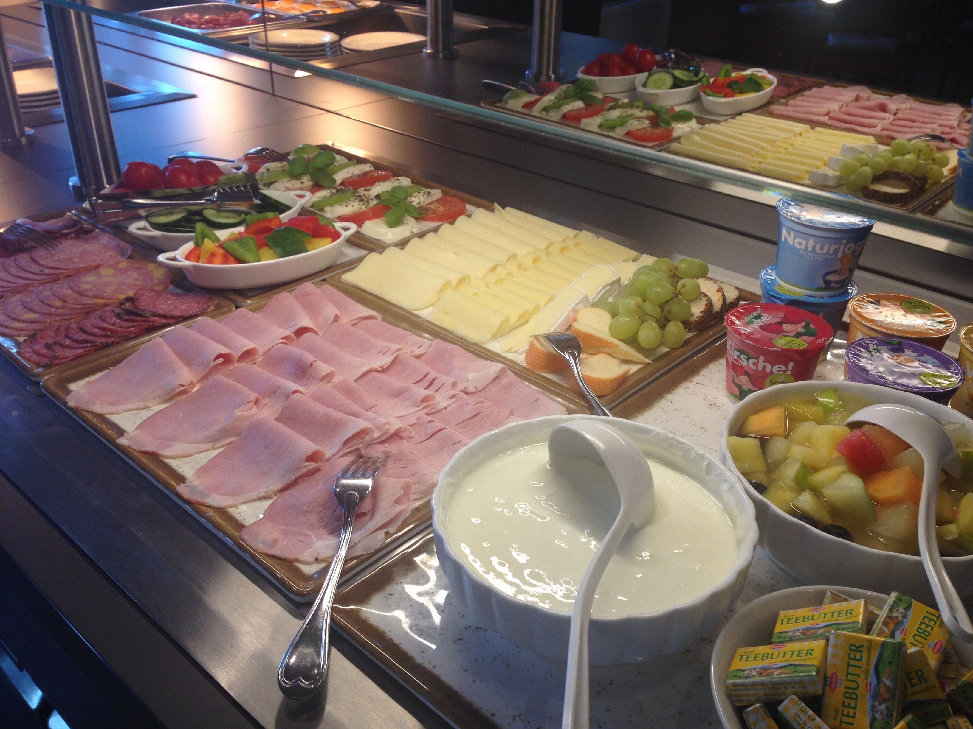 A buffet with various food items including meats, cheeses, and fruits.