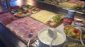 A buffet with various food items including meats, cheeses, and fruits.