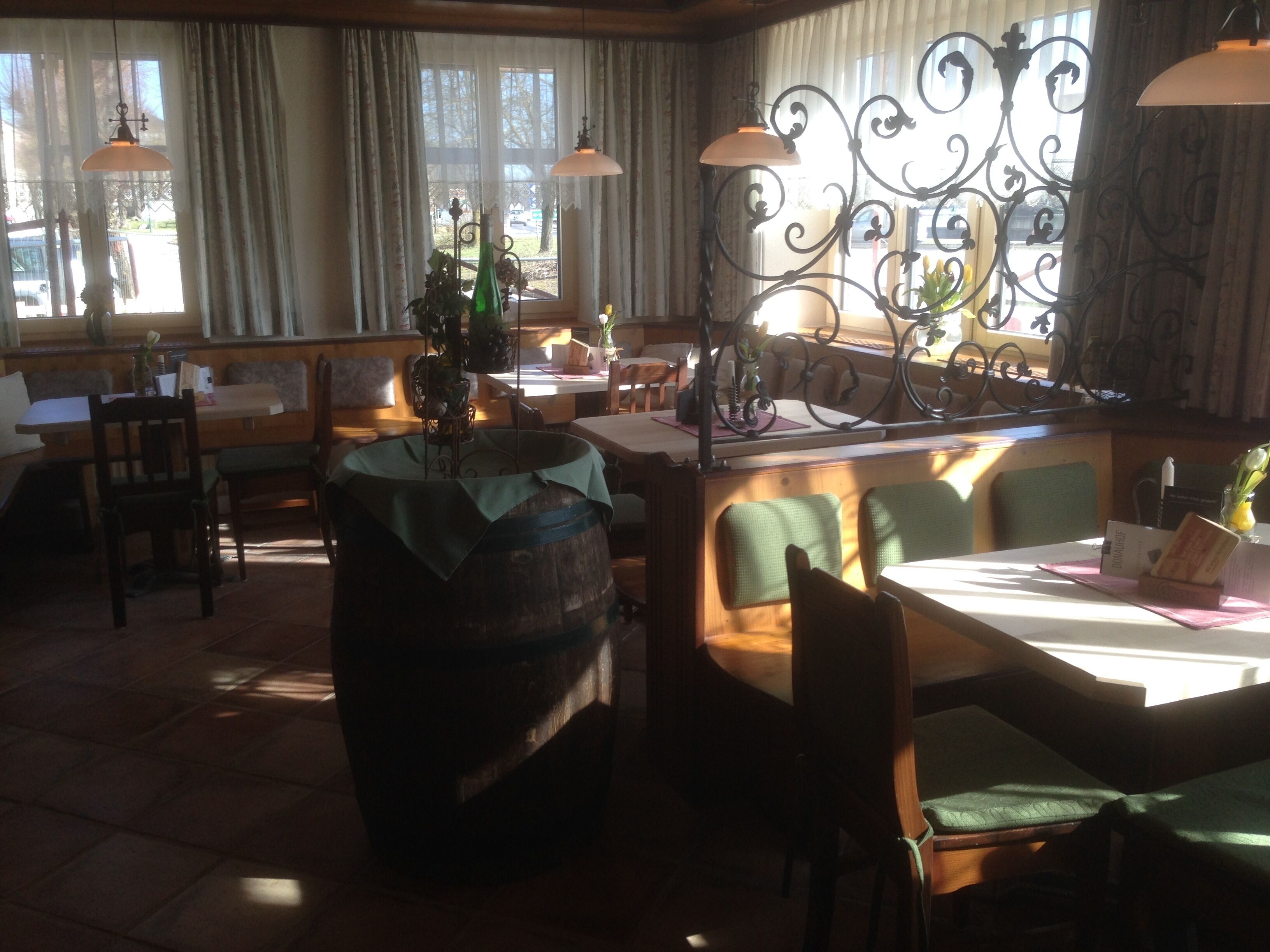 Un restaurant avec des meubles en bois, un grand tonneau et une balustrade en fer forgé.