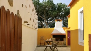 Une cour bordée d’un mur de pierre, d’une clôture en bois et d’un bâtiment jaune doté d’une cheminée.