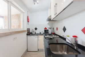 A compact kitchen with a dishwasher, microwave, and stove.