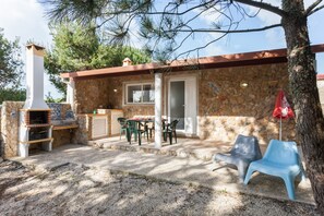 A stone building with a barbecue area, outdoor seating, and a door.