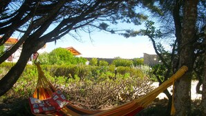 A hammock tied between trees in a garden with a house in the background. - FLH Garden House near Ericeira II (São João das Lampas)
