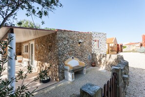 Ein Steinhaus mit einer Bank und einer kleinen Terrasse.