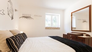 A bedroom with a bed, a dresser, a mirror, and a window. - FLH Garden House near Ericeira II (São João das Lampas)