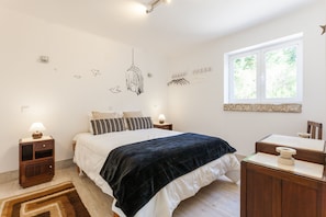 Une chambre à coucher comprenant un lit, des tables de chevet, un bureau, une fenêtre et des œuvres d’art murales.