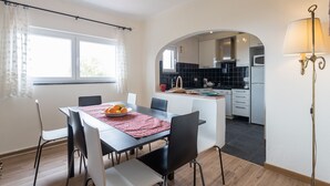 Une cuisine moderne avec des carreaux noirs, un coin repas agrémenté d’un set de table rouge et une table blanche.