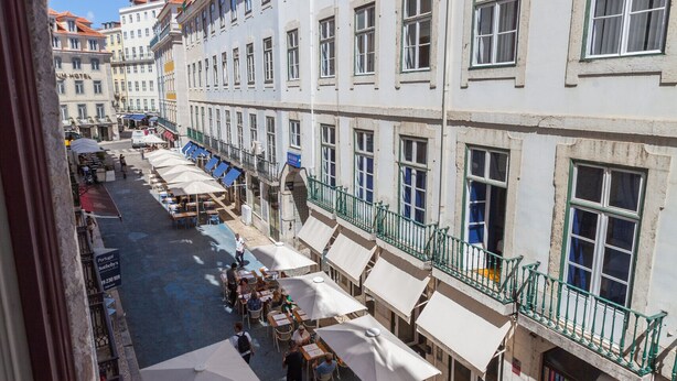 Un cortile con posti a sedere all'aperto, ombrelloni bianchi e un caffè.
