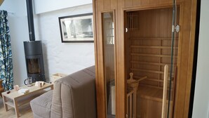 Una sala acogedora con un sofá, una mesa de madera con una tetera y una chimenea.