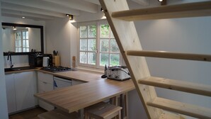 Una cocina con una mesa de madera, una estufa y un ventanal.
