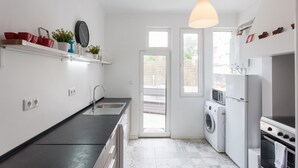 Een moderne keuken met een spoelbak, fornuis en magnetron. Er zijn twee ramen en een deur naar een terras.