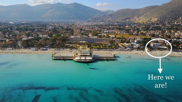 A coastal cityscape with a prominent waterfront area featuring a pier with a building structure. - Villa Masetta - Luxury Suite (Palermo)
