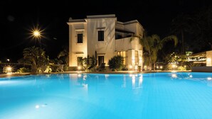 A swimming pool with a modern building in the background. - Villa Masetta - Luxury Suite (Palermo)