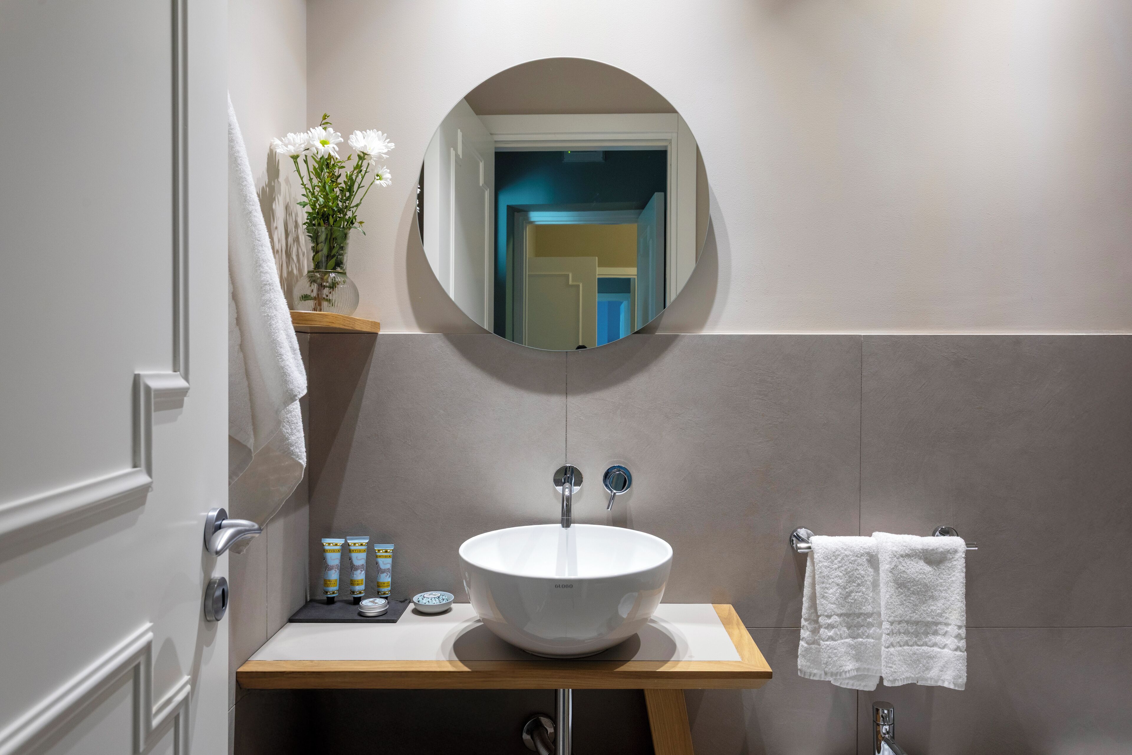 A bathroom with a white sink, a mirror, and a towel rack.
