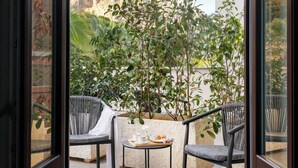 A glass-enclosed patio with two chairs, a small table, and potted plants. - Villa Masetta - Luxury Suite (Palermo)