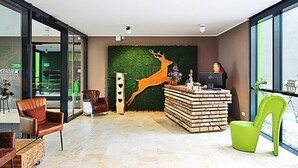 Un espace d’accueil moderne agrémenté d’un mur végétal, d’une grande sculpture de cerf et d’un bureau équipé d’un ordinateur.