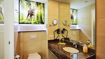 A bathroom with a large mirror, a sink, and a toilet. There is a poster of a deer on the wall.