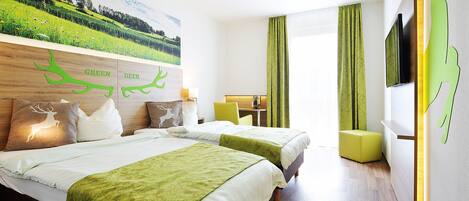 Une chambre d’hôtel avec deux lits, un bureau et une décoration aux couleurs vertes.