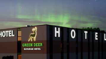 Un bâtiment d'hôtel avec une enseigne indiquant « Green Deer Bavarian Hotel » et le mot « HÔTEL » sur la façade.