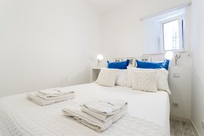 Un lit bien fait, avec du linge de lit blanc et une serviette pliée posée sur le côté.