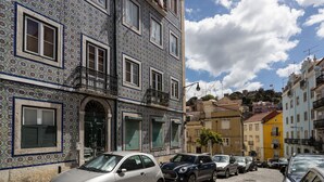 Rua de paralelepípedos ladeada por edifícios com fachadas em azulejos tradicionais azul e branco.