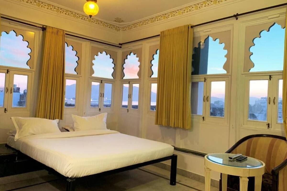 Een hotelkamer met een bed, een stoel, een klein tafeltje en decoratieve ramen.