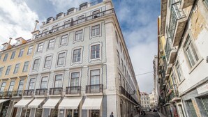 Un immeuble à plusieurs étages, avec une rangée de boutiques au rez-de-chaussée et une promenade piétonne.