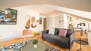 Un salon moderne avec un canapé gris, une table basse ronde et un tapis à motifs.