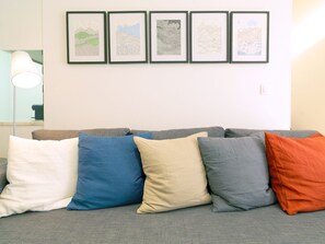 Un canapé gris agrémenté de cinq coussins : un blanc, un bleu, un beige, un gris et un orange.