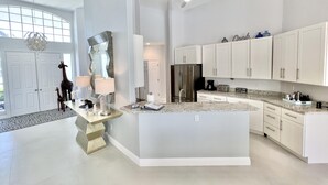 Een ruime keuken met witte kasten, een groot eiland en een moderne plafondventilator.