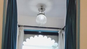 Una habitación con cama, dos almohadas, ventana con vista a edificios y cortinas.