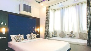 Un dormitorio con una cama grande, un banco empotrado, un aire acondicionado instalado en la pared y una ventana con cortinas.