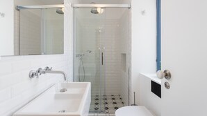 A modern bathroom with a glass-enclosed shower, a white sink, and a toilet.