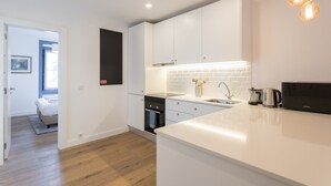 A modern kitchen with white cabinets, a built-in oven, and a coffee maker.