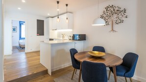 A modern kitchen with white cabinets, a built-in microwave, and pendant lights.